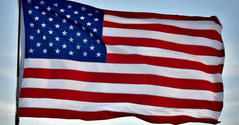 US flag with blue sky and white clouds background during daytime